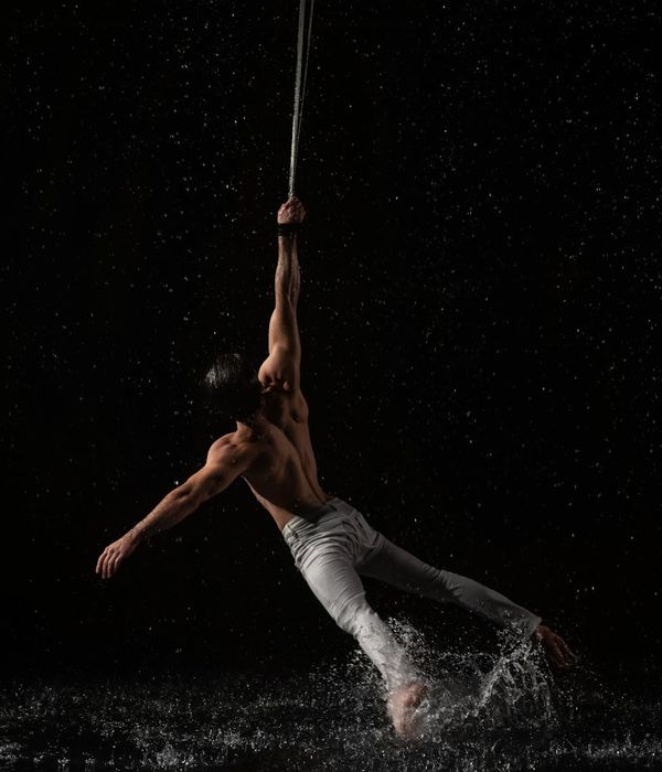 Man performing a controlled strength exercise in a minimalist dark environment.